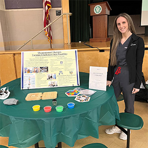Gena presents her cognitive healing research on a poster at an event.