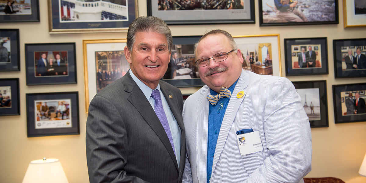 Kirby and Senator Joe Manchin smiling at the camera and shaking hands