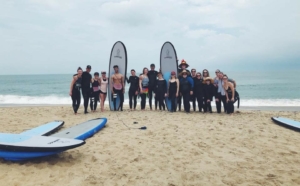 Cancer survivors in group photo on beach after learning to surf with nonprofit organization First Descents.